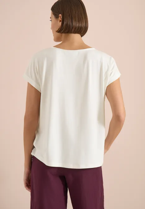 femme vue de dos portant un t-shirt blanc à manches courtes et un pantalon bordeaux