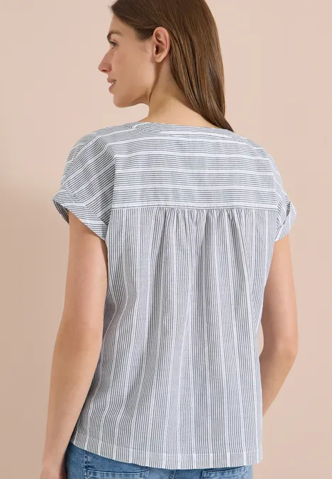 Rückansicht einer Frau in einer grauen, kurzärmlichen Bluse mit weißen Streifen