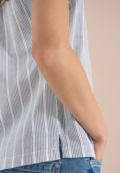 Seitliche Ansicht eines Oberkörpers in blau-weiß gestreiftem Top, Hand in Jeans-Tasche.