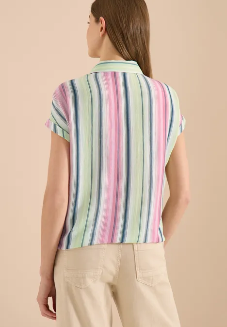 Hemdbluse mit Streifen und Knoten vanilla white Frau steht mit dem Rücken zur Kamera, trägt kurzärmliges Poloshirt mit pastellfarbenen Streifen und helle Hose.