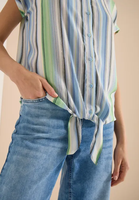 Hemdbluse mit Streifen und Knoten light sky blue Person trägt blaue Jeans und gestreiftes Hemd, geknotet an der Taille, Hand in Tasche.