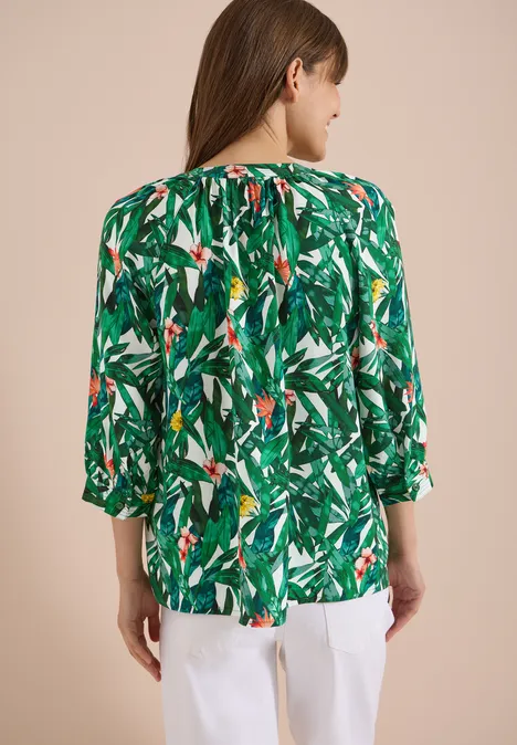 3/4-Arm Tunika mit Split Neck und Print khaki Rückansicht einer Person mit einer grünen, tropisch gemusterten Bluse und weißen Hosen.