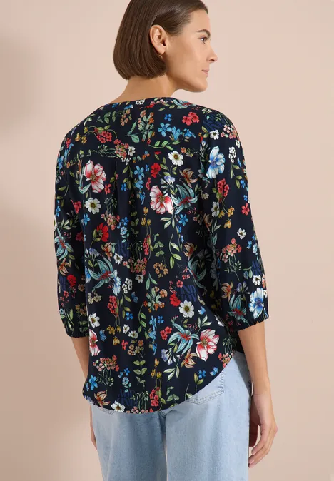 3/4-Arm Bluse mit Split Neck und Print universal blue Frau von hinten in dunkelblauer, bunt geblümter Bluse mit 3/4-Ärmeln und hellen Jeans.