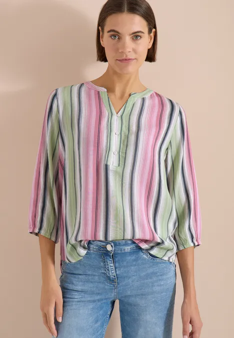 3/4-Arm Bluse mit Multicolor Streifen vanilla white Frau in bunter, gestreifter Bluse und Jeans vor neutralem Hintergrund.