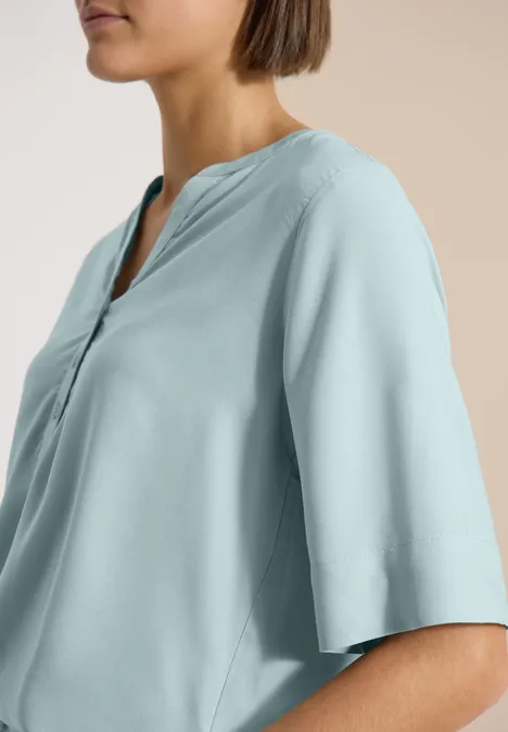 Blouse met korte mouwen en gespleten hals crystal mint Profilansicht einer Frau in pastellblauer, locker sitzender Bluse mit V-Ausschnitt und halb langen Ärmeln.