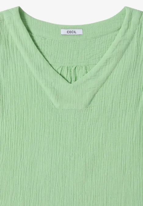 Ein hellgrünes Damen-Shirt mit V-Ausschnitt und strukturierter Rippoptik, kurz geschnitten und lässig.