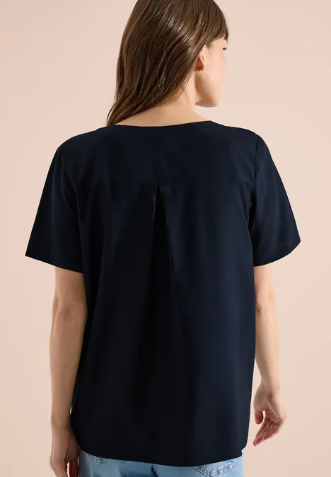 Rückenansicht einer Frau in lockerem dunkelblauem Kurzarmshirt