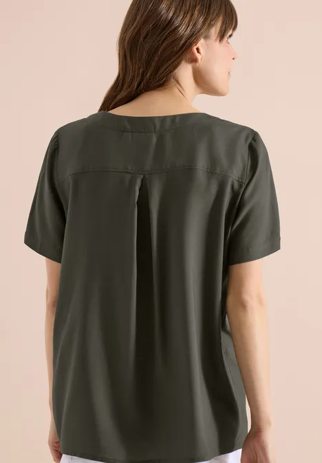 Frau von hinten im olivgrünen Kurzarmshirt mit Rückenfalte.