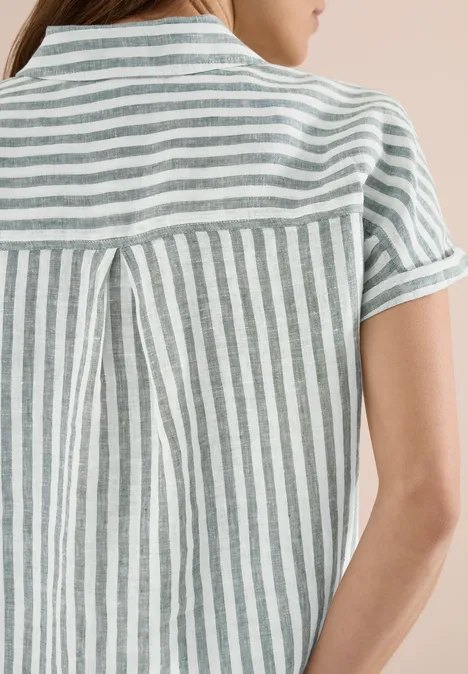 Vue de dos d’une personne portant un chemisier à manches courtes blanc et gris rayé avec pli au dos.