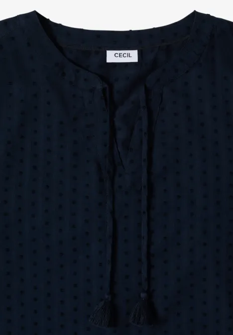 Donkerblauwe damesblouse met subtiel stippenpatroon, korte opstaande kraag en sierlinten met kwastjes.