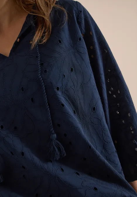 Nahaufnahme einer dunkelblauen Bluse mit Lochstickerei, V-Ausschnitt und Quasten