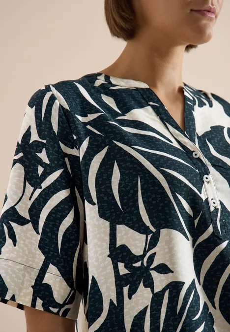 Blouse met korte mouwen en gespleten hals palm breeze green Person trägt ein dunkelblau-weiß gemustertes Hemd mit tropischem Blattmotiv.