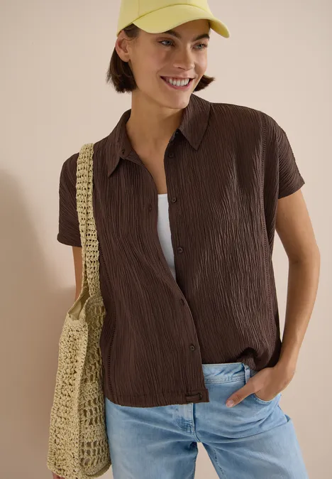 Dropped Shoulder Hemdbluse in Unifarbe brown cacao Person trägt braunes Kurzarmhemd, weiße Unterziehbluse, Jeans und gelbe Mütze, dazu eine gehäkelte Tasche.