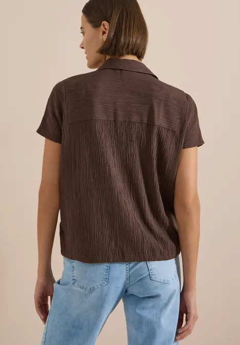 Dropped Shoulder Hemdbluse in Unifarbe brown cacao Frau von hinten in braunem Kurzarmhemd mit hellem Kragen und hellblauen Jeans.