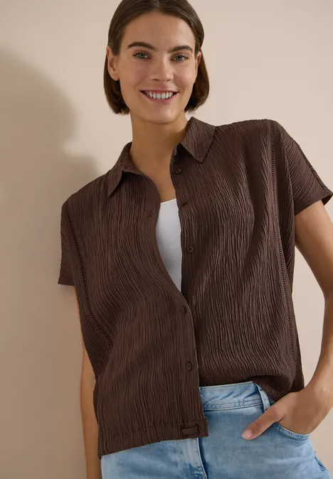 Dropped Shoulder Hemdbluse in Unifarbe brown cacao Frau trägt braunes, strukturiertes Kurzarmhemd über weißem Shirt und blaue Jeans, Hand in Tasche.