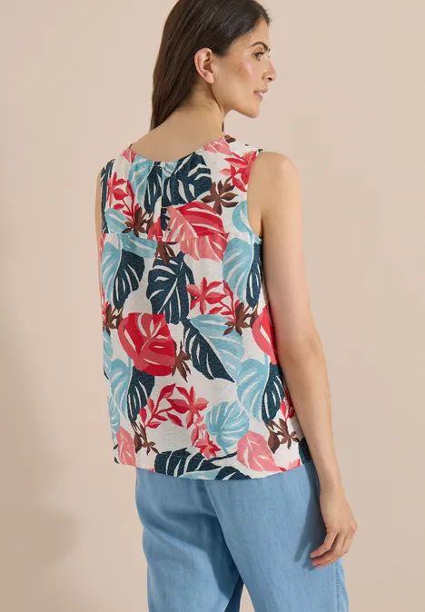 Blouse met ronde hals en bladerenprint light alabaster white Vrouw van achteren in een mouwloze top met kleurrijke bladprint en wijde blauwe broek.