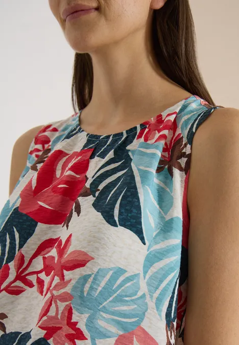 Blouse met ronde hals en bladerenprint light alabaster white Vrouw draagt mouwloos topje met kleurrijke bloemen- en bladerenprint.