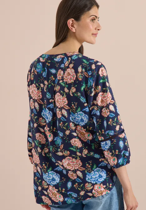 3/4-Arm Tunika mit floralem Muster urban dark blue Frau von hinten in lockerem, dunkelblauem Oberteil mit buntem Blumenmuster und 3/4-Ärmeln.