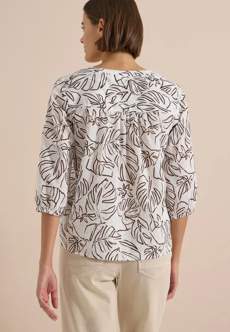 3/4-Arm Tunika mit Blätterprint light alabaster white Frau von hinten in weißer Bluse mit schwarzem Blattmuster und hellen Hosen.