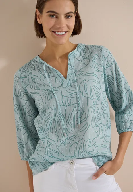 3/4-Arm Tunika mit Blätterprint crystal mint Frau in pastellgrünem, gemustertem Hemd mit 3/4-Ärmeln, locker in weiße Hose gesteckt.