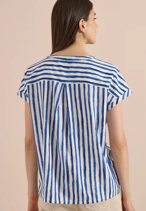 Dropped Shoulder Bluse mit Streifen urban navy blue Frau von hinten in weiß-blau gestreiftem Kurzarmshirt vor beigem Hintergrund.