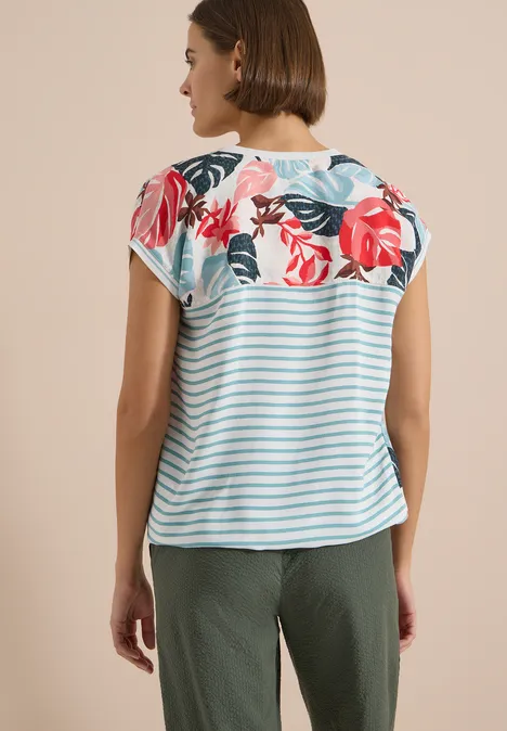 Bluse mit Split Neck und Printmix light alabaster white Rückansicht einer Frau mit Kurzarmshirt in blau-weißen Streifen und Blumenmuster, dazu olivgrüne Hose.