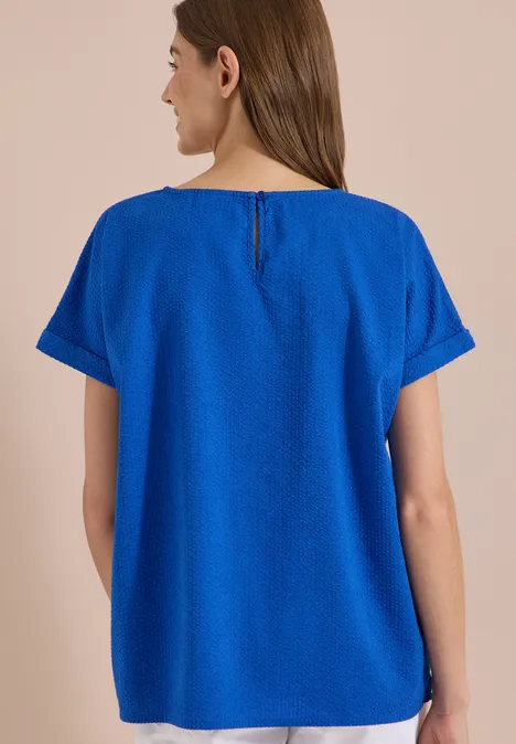 Blouse met ronde hals en knoopdetail surf blue Eine Frau von hinten trägt ein lockeres, kurzärmliges, knallblaues Oberteil mit rundem Ausschnitt.