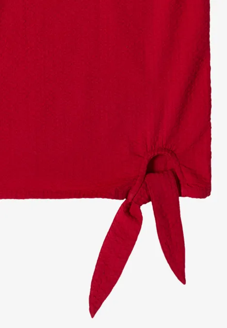 Roter, strukturierter Stoff mit Knoten an der Ecke.