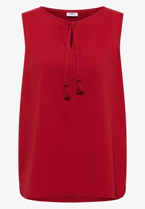 Top rouge sans manches texturé avec cordons à nouer et pompons.