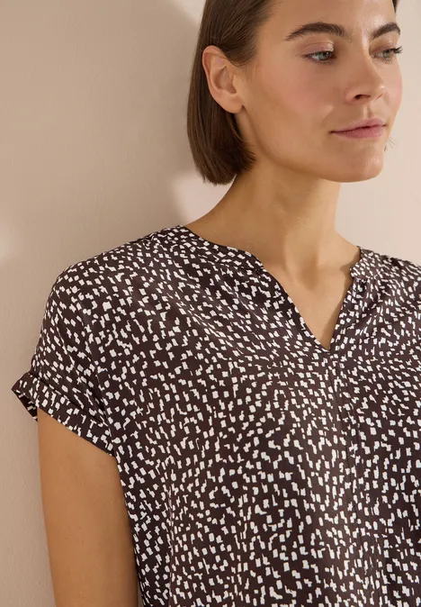 Blouse met hangende schouder en print brown cacao Damesblouse met korte mouwen in bruin met onregelmatige witte stippen en V-hals.