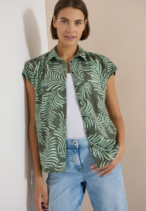 Kurzarm Hemdbluse mit Print khaki Person trägt ein kurzärmliges, grün gemustertes Hemd mit Blattmotiv über weiße Bluse und Jeans.