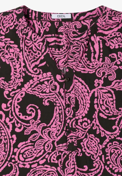 Top noir à motifs baroques roses en volutes et décolleté en V.