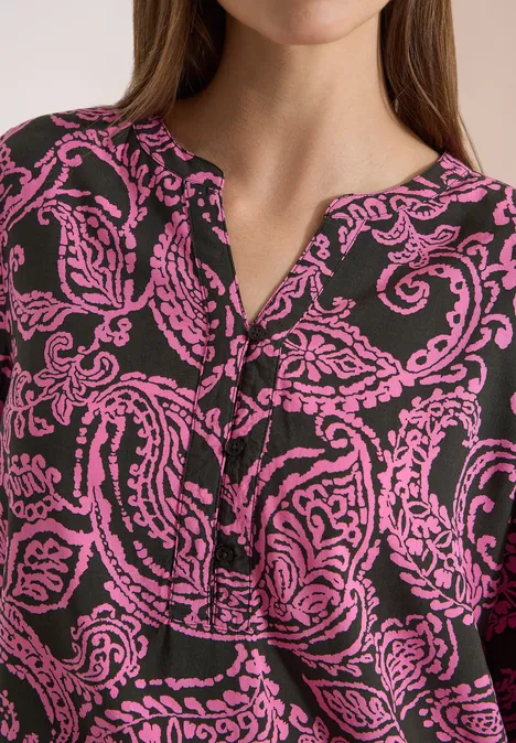 Gros plan sur un chemisier noir à imprimé cachemire rose, encolure en V.