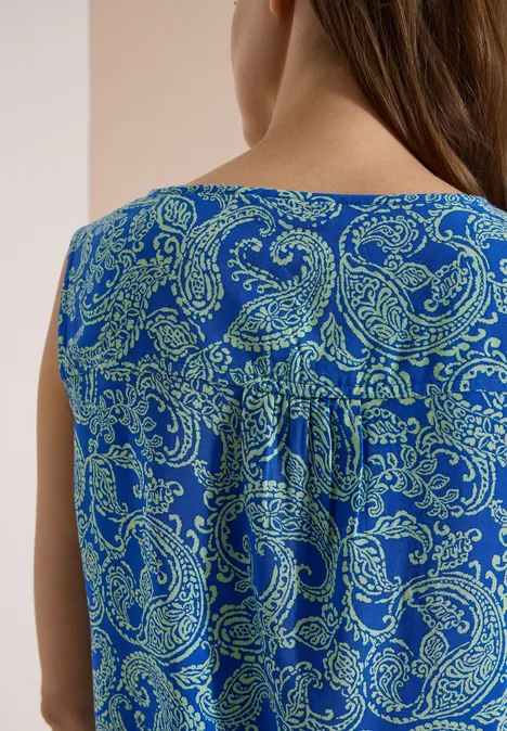 Haut chemisier à col fendu et imprimé surf blue Vue de dos d’une personne portant un haut sans manches bleu à motif paisley vert.