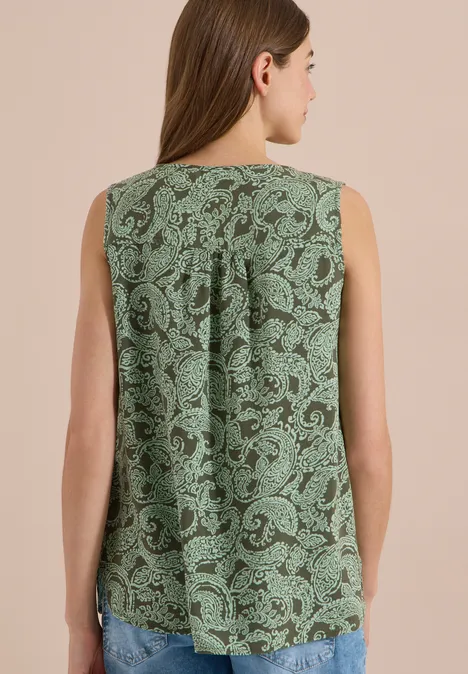 Vue de dos d'une femme portant un haut sans manches vert à motif cachemire ample.