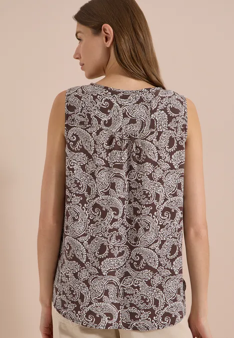Frau von hinten in ärmellosem, dunkelrotem Top mit weißem Paisley-Muster.