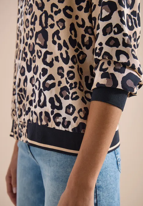 Personne portant un pull motif léopard à manches longues et un jean.