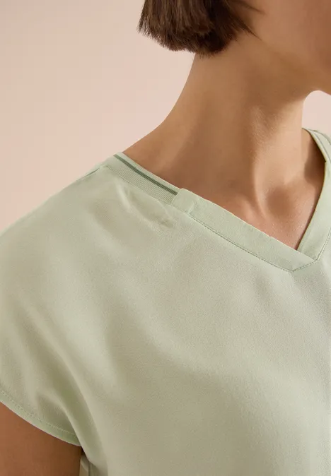 Kurzarm Blusenshirt mit Strukturmix raw matcha lime Nahaufnahme eines hellgrünen V-Ausschnitt-Shirts, das Schulter und Halsbereich zeigt.