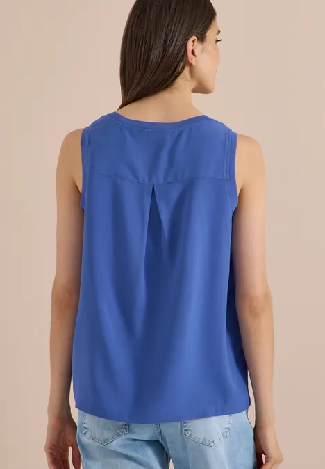 Blusentop mit Rundhals und Rippdetails deep river blue Frau von hinten mit ärmelloser, königsblauer Bluse und heller Jeans vor beigem Hintergrund.