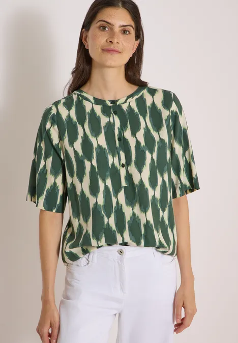 Kurzarm Bluse mit Rundhals und Print vanilla white Frau trägt grün-weiß gemustertes Kurzarmshirt mit weißen Hosen.