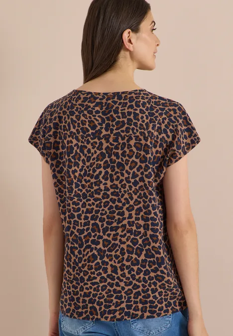 Frau von hinten in kurzärmeligem, braun-schwarzem Leoparden-Print-Shirt.