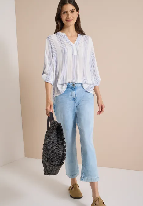 3/4-Arm Bluse mit Turn-Up und Streifen deep river blue Frau trägt hellblau-weiß gestreifte Bluse, lockere Jeans, beige Slipper und hält einen schwarzen, gewebten Shopper.