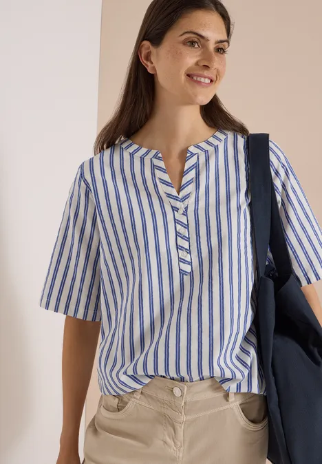 Halbarm Bluse mit Split Neck und Streifen deep river blue Eine Frau trägt eine blau-weiß gestreifte Bluse, lächelt und hat eine dunkelblaue Tasche über der Schulter.