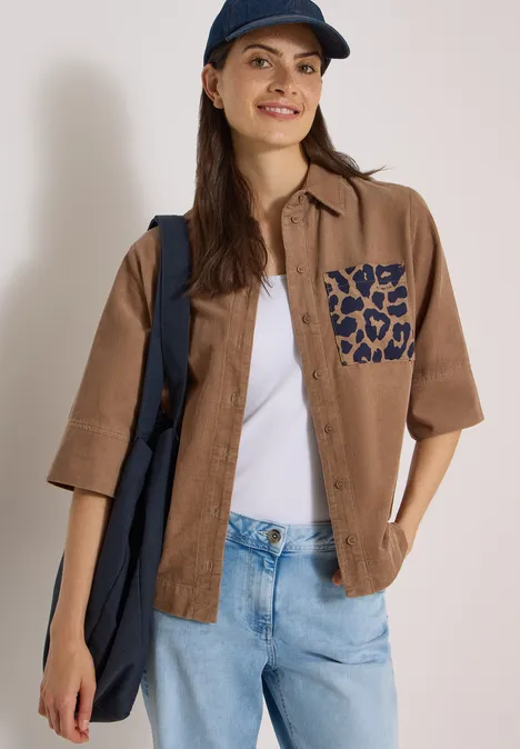 Chemisier à manches courtes en velours côtelé avec poche poitrine creamy mocha Junge Frau in braunem Kurzarmhemd mit Leoparden-Tasche, weißem Top, Jeans, navy Cap und Tasche.