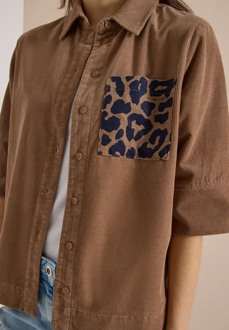 Chemisier à manches courtes en velours côtelé avec poche poitrine creamy mocha Braunes Hemd mit kurzen Ärmeln und auffälliger dunkelblauer Leoprint-Tasche auf der Brust.