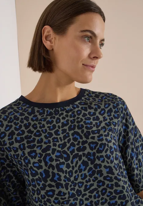 Nahaufnahme einer Frau im blau-schwarzen Leo-Pullover mit schulterlangem Haar.