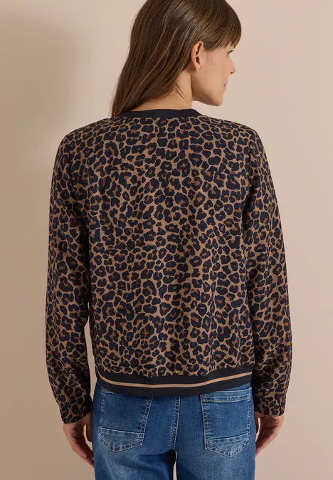 Vrouw van achteren in een leopardprint trui voor een neutrale achtergrond.