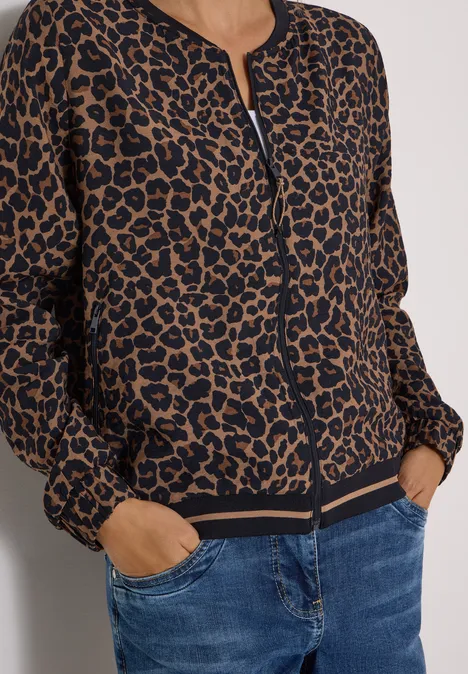 Bomberjack met luipaardprint, rits en zakken, gecombineerd met een blauwe spijkerbroek.