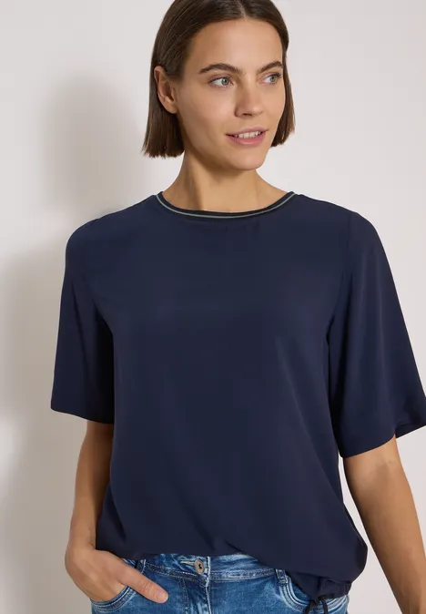 Kurzarm Blusenshirt mit Rundhals urban dark blue Frau mit kurzem braunen Haar in dunkelblauem T-Shirt und Jeans, schaut leicht lächelnd zur Seite.