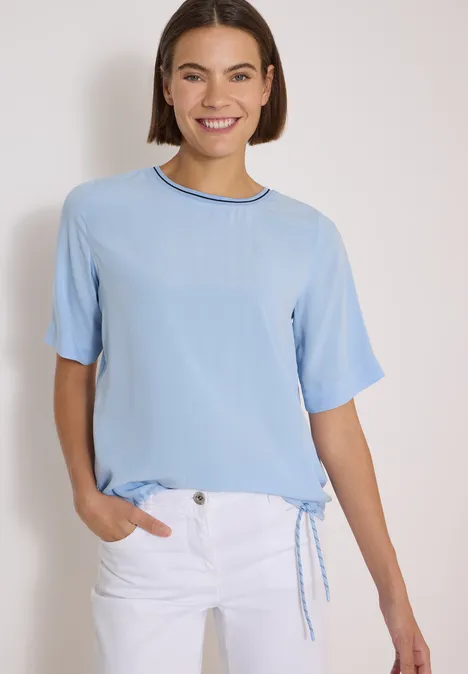 Kurzarm Blusenshirt mit Rundhals easy blue Eine lächelnde Frau trägt eine hellblaue Kurzarmbluse mit Rundhalsausschnitt und weiße Hose.